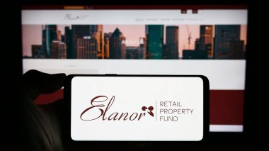 Stuttgart, Almanya - 10-29-2023: Avustralyalı şirket Elanor Commercial Property Fund 'un logosuna sahip cep telefonu sahibi kişi iş sayfasının önünde. Telefon ekranına odaklan.