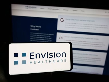 Stuttgart, Almanya - 10-29-2023: ABD 'li hastane şirketi Envision Healthcare' in logosuna sahip akıllı telefon sahibi kişi web sitesi önünde. Telefon ekranına odaklan.