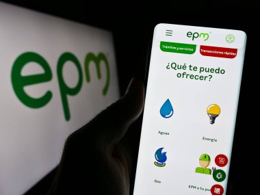 Stuttgart, Almanya - 10-29-2023: Kolombiyalı Empresas Publicas de Medellin (EPM) şirketinin logolu web sayfası ile akıllı telefon tutan kişi. Telefon ekranının merkezine odaklan.