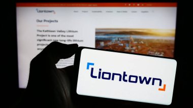 Stuttgart, Germany - 10-29-2023: Person holding smartphone with logo of Australian mining company Liontown Resources Limited in front of website. Focus on phone display. clipart