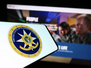 Stuttgart, Germany - 10-29-2023: Smartphone with seal of agency group United States Intelligence Community (IC) in front of website. Focus on center-left of phone display. clipart