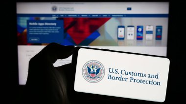 Stuttgart, Almanya - 10-29-2023: İnternet sayfası önünde ABD Gümrük ve Sınır Koruma Teşkilatı (CBP) mührü taşıyan kişi. Telefon ekranına odaklan.