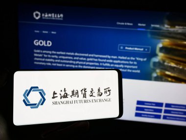 Stuttgart, Almanya - 10-30-2023: Çin Şangay Gelecek Borsası (ŞFE) logosu olan cep telefonu sahibi kişi iş sayfasının önünde. Telefon ekranına odaklan.