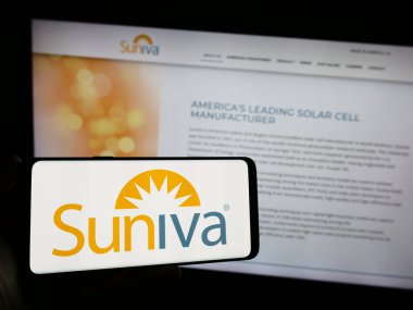 Stuttgart, Almanya - 10-30-2023: İş sayfası önünde ABD 'li fotovoltaik şirketi Suniva Inc.' in logosunun bulunduğu cep telefonu sahibi kişi. Telefon ekranına odaklan.