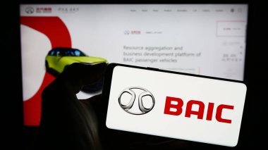 Stuttgart, Almanya - 10-30-2023: Çinli şirket Beijing Automotive Group Co. Ltd. (BAIC) 'nin logosuyla cep telefonu tutan kişi. Telefon ekranına odaklan.