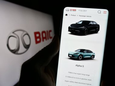 Stuttgart, Almanya - 10-30-2023: Çinli şirket Beijing Automotive Group Co. Ltd. (BAIC) 'nin logolu web sayfası ile cep telefonu tutan kişi. Telefon ekranının merkezine odaklan.