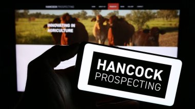 Stuttgart, Almanya - 10-31-2023: Avustralyalı maden şirketi Hancock Prospecting Pty 'nin logosuyla cep telefonu tutan kişi. Ltd. Web sayfasının önünde. Telefon ekranına odaklan.