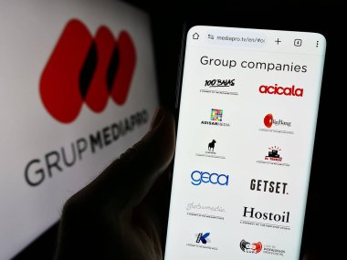 Stuttgart, Almanya - 10-31-2023: İspanyol multimedya şirketi Mediapro Group 'un web sitesi ile logo önünde cep telefonu tutan kişi. Telefon ekranının merkezine odaklan.