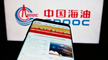 Stuttgart, Germany - 09-10-2023: Smartphone with webpage of China National Offshore Oil Corporation (CNOOC) on screen in front of logo. Focus on top-left of phone display. clipart