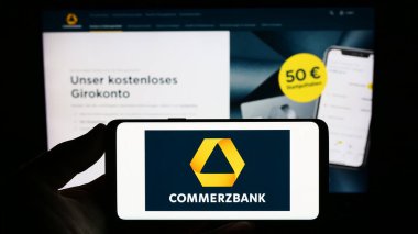 Stuttgart, Almanya - 09-10-2023: Alman finans şirketi Commerzbank AG 'nin logosunu elinde tutan kişi web sitesinin önünde ekranda. Telefon ekranına odaklan.