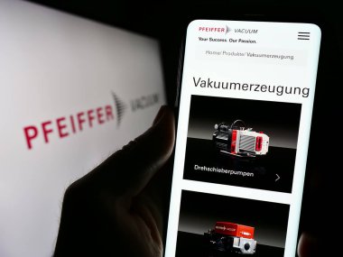 Stuttgart, Almanya - 09-10-2023: Alman Pfeiffer Vacuum Technology AG şirketinin internet sayfası ile cep telefonu tutan kişi logolu ekranda. Telefon ekranının merkezine odaklan.