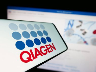 Stuttgart, Almanya - 09-10-2023: Biyoteknoloji şirketi Qiagen N.V. 'nin logosunun yer aldığı cep telefonu iş sitesinin önünde ekranda. Telefon ekranının merkez soluna odaklan.