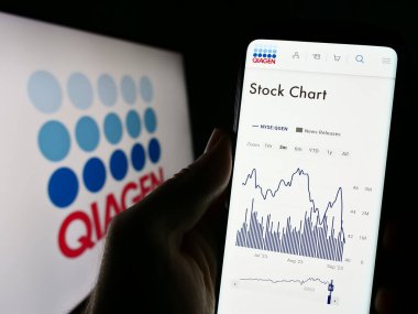 Stuttgart, Almanya - 09-10-2023: İş logosu önünde ekranda biyoteknoloji şirketi Qiagen NV 'nin web sayfası bulunan kişi. Telefon ekranının merkezine odaklan.