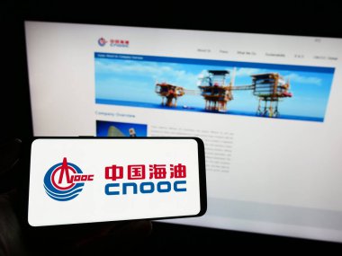 Stuttgart, Almanya - 09-10-2023: İnternet sayfasının önünde Çin Ulusal Offshore Oil Corporation (CNOOC) logosu olan cep telefonu sahibi kişi. Telefon ekranına odaklan.