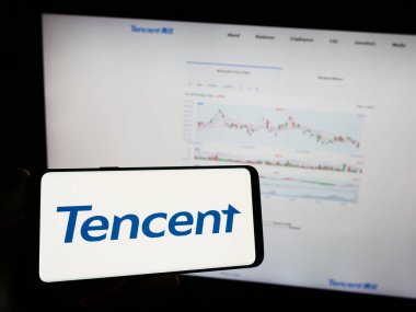 Stuttgart, Almanya - 09-11-2023: Çinli şirket Tencent Holding Ltd. 'nin logosunun bulunduğu cep telefonu sahibi kişi iş sayfasının önünde ekranda. Telefon ekranına odaklan.