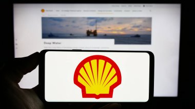 Stuttgart, Almanya - 09-11-2023: İngiliz petrol ve doğalgaz şirketi Shell plc 'nin logosu olan cep telefonu sahibi kişi iş sayfasının önünde ekranda. Telefon ekranına odaklan.