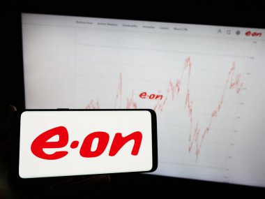 Stuttgart, Almanya - 09-11-2023: Alman enerji şirketi E.ON SE 'nin logosunun bulunduğu cep telefonu sahibi kişi iş sayfasının önünde ekranda. Telefon ekranına odaklan.