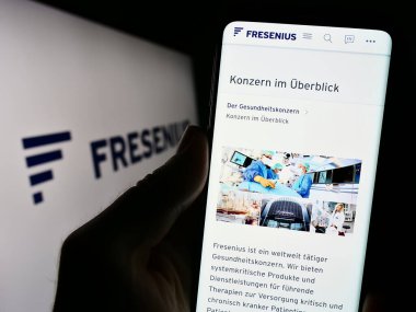 Stuttgart, Almanya - 09-11-2023: Alman sağlık şirketi Fresenius SE Co. KGaA 'nın internet sitesi ile cep telefonu tutan kişi logolu ekranda. Telefon ekranının merkezine odaklan.
