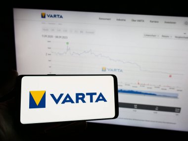 Stuttgart, Almanya - 09-11-2023: Alman batarya şirketi Varta AG 'nin logosuyla cep telefonu sahibi kişi iş sayfasının önünde ekranda. Telefon ekranına odaklan.
