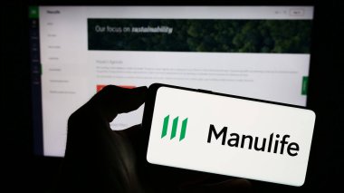 Stuttgart, Germany - 09-11-2023: Person holding smartphone with logo of Canadian company Manulife Financial Corporation on screen in front of website. Focus on phone display. clipart