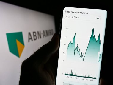 Stuttgart, Germany - 09-11-2023: Person holding smartphone with website of Dutch financial company ABN AMRO Bank N.V. on screen in front of logo. Focus on center of phone display. clipart