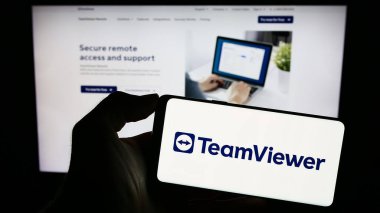 Stuttgart, Almanya - 09-13-2023: Alman yazılım şirketi TeamViewer SE 'nin logosuyla cep telefonu sahibi kişi iş sayfasının önünde ekranda. Telefon ekranına odaklan.