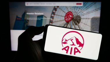 Stuttgart, Almanya - 09-13-2023: Sigorta şirketi AIA Group Limited 'in logosuna sahip cep telefonu sahibi kişi iş sayfasının önünde ekranda. Telefon ekranına odaklan.