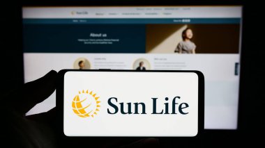 Stuttgart, Almanya - 09-14-2023: Kanadalı Sun Life Financial Inc. şirketinin logosunu elinde tutan kişi web sitesinin önünde ekranda. Telefon ekranına odaklan.
