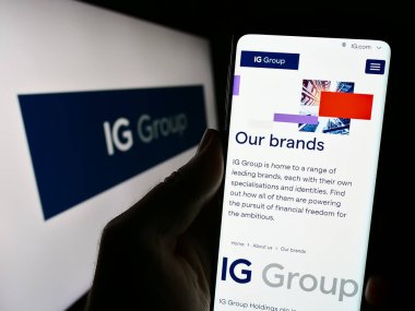 Stuttgart, Almanya - 09-14-2023: İngiliz ticaret şirketi IG Group Holding 'in internet sayfası ile cep telefonu tutan kişi logo ile ekranda. Telefon ekranının merkezine odaklan.