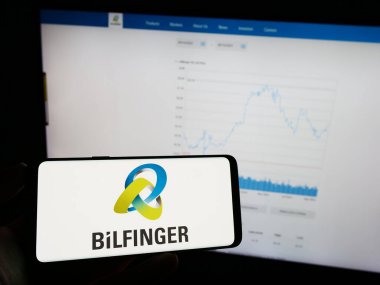 Stuttgart, Almanya - 09-14-2023: Alman inşaat şirketi Bilfinger SE 'nin logosunun bulunduğu cep telefonu sahibi kişi iş sayfasının önünde ekranda. Telefon ekranına odaklan.