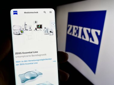 Stuttgart, Almanya - 09-17-2023: Ekranda tıbbi teknoloji şirketi Carl Zeiss Meditec AG 'nin web sayfası bulunan cep telefonu sahibi kişi. Telefon ekranının merkezine odaklan.