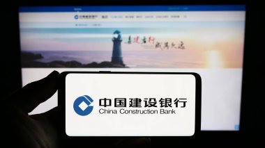 Stuttgart, Almanya - 09-17-2023: İnternet sitesi önünde Çin İnşaat Bankası Şirketi 'nin (CCB) logosuna sahip akıllı telefon sahibi kişi. Telefon ekranına odaklan.