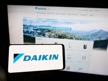 Stuttgart, Almanya - 09-17-2023: Japon şirketi Daikin Industries Ltd. 'nin logosuyla cep telefonu sahibi kişi iş sayfasının önünde ekranda. Telefon ekranına odaklan.