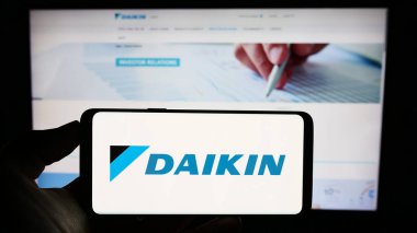 Stuttgart, Almanya - 09-17-2023: Japon şirketi Daikin Industries Ltd. 'nin logosuyla cep telefonu sahibi kişi iş sayfasının önünde ekranda. Telefon ekranına odaklan.