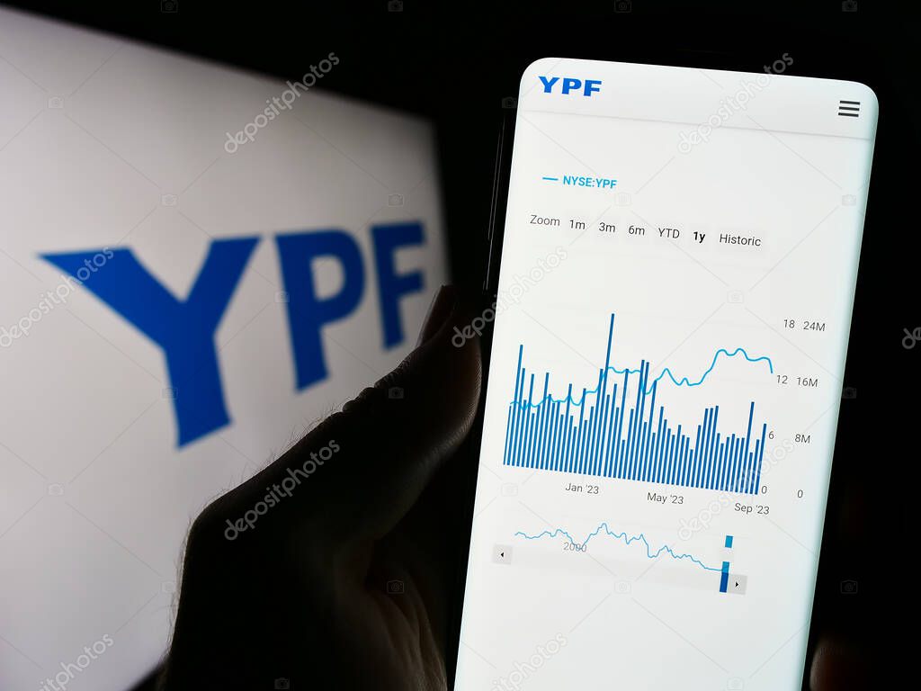 Stuttgart, Germany - 09-11-2023: Person holding cellphone with webpage of Argentinian petroleum company YPF S.A. on screen in front of logo. Focus on center of phone display.