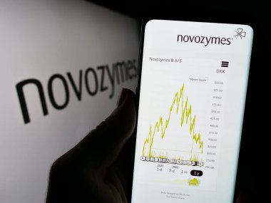 Stuttgart, Almanya - 09-17-2023: Danimarkalı biyoteknoloji şirketi Novozymes AS 'in web sayfası ile cep telefonu tutan kişi logonun önünde ekranda. Telefon ekranının merkezine odaklan.