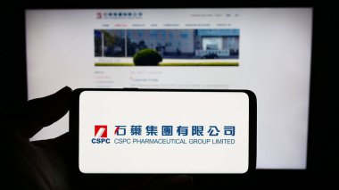 Stuttgart, Almanya - 09-17-2023: CSPC Pharmaceutical Group Limited şirketinin logosuna sahip akıllı telefon sahibi kişi web sitesi önünde ekranda. Telefon ekranına odaklan.