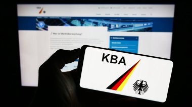 Stuttgart, Almanya - 09-17-2023: İnternet sayfası önünde Alman federal ajansı Kraftfahrt-Bundesamt 'ın (KBA) logosunu elinde tutan kişi. Telefon ekranına odaklan.