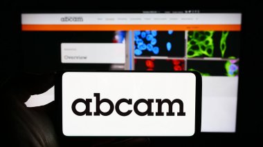 Stuttgart, Almanya - 09-17-2023: İngiliz biyoteknoloji şirketi Abcam plc 'in logosuyla cep telefonu sahibi kişi iş sayfasının önünde ekranda. Telefon ekranına odaklan.