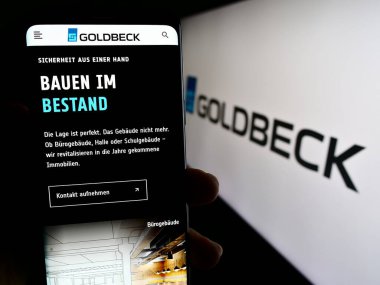 Stuttgart, Almanya - 09-17-2023: Alman inşaat şirketi Goldbeck GmbH 'in web sayfası ile akıllı telefonu olan kişi logonun önünde ekranda. Telefon ekranının merkezine odaklan.
