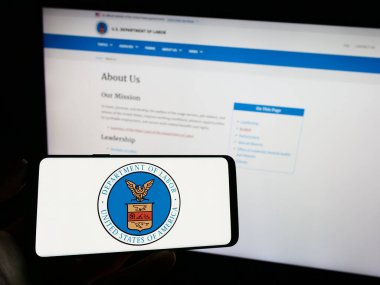 Stuttgart, Almanya - 09-20-2023: ABD Çalışma Bakanlığı 'nın (US DOL) mührünü taşıyan cep telefonu İnternet sayfası önünde ekranda. Telefon ekranına odaklan.