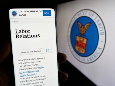 Stuttgart, Almanya - 09-20-2023: Birleşik Devletler Çalışma Bakanlığı 'nın (US DOL) web sayfası ile çalışan kişi ekranda mühürlü. Telefon ekranının merkezine odaklan.