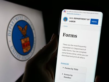 Stuttgart, Almanya - 09-20-2023: ABD Çalışma Bakanlığı 'nın (US DOL) web sayfası ile cep telefonu tutan kişi, SEAL' in önünde ekranda. Telefon ekranının merkezine odaklan.