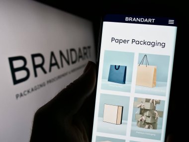 Stuttgart, Almanya - 09-20-2023: İtalyan ambalaj şirketi Brandart S.P.A. 'nın web sayfası ile akıllı telefon tutan kişi logonun önünde ekranda. Telefon ekranının merkezine odaklan.