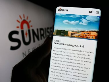 Stuttgart, Almanya - 09-20-2023: Çinli şirket Sunrise New Energy Co. Ltd. nin internet sayfası ile cep telefonu tutan kişi logonun önünde ekranda. Telefon ekranının merkezine odaklan.