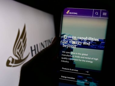 Stuttgart, Almanya - 09-20-2023: İngiliz enerji teknoloji şirketi Hunting plc 'nin web sitesi olan akıllı telefonu ekranda logolu kişi. Telefon ekranının merkezine odaklan.