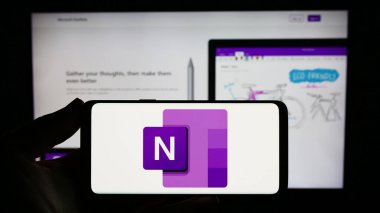 Stuttgart, Almanya - 09-21-2023: İnternet sitesinin önünde üzerinde not alan Microsoft OneNote yazılımı logosu olan akıllı telefon sahibi kişi. Telefon ekranına odaklan.
