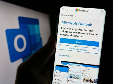 Stuttgart, Almanya - 09-21-2023: Logo önündeki ekranda Microsoft Outlook 'un e-posta yazılımının web sayfası olan cep telefonu sahibi kişi. Telefon ekranının merkezine odaklan.