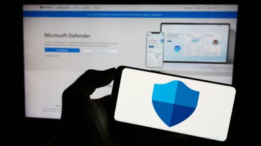Stuttgart, Almanya - 09-21-2023: Güvenlik yazılımı logosu olan cep telefonu sahibi kişi Microsoft Defender Antivirus web sayfası önünde ekranda. Telefon ekranına odaklan.