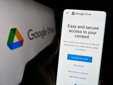 Stuttgart, Almanya - 09-22-2023: Cep telefonu tutan kişi, Google Drive dosya depolama platformunun web sayfası logonun önünde ekranda. Telefon ekranının merkezine odaklan.